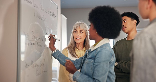 Maths teacher explaining work on a whiteboard
